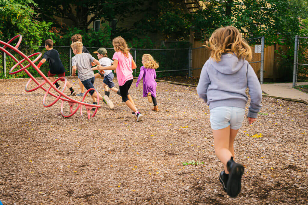 alt='school age students playing outside in the yard'