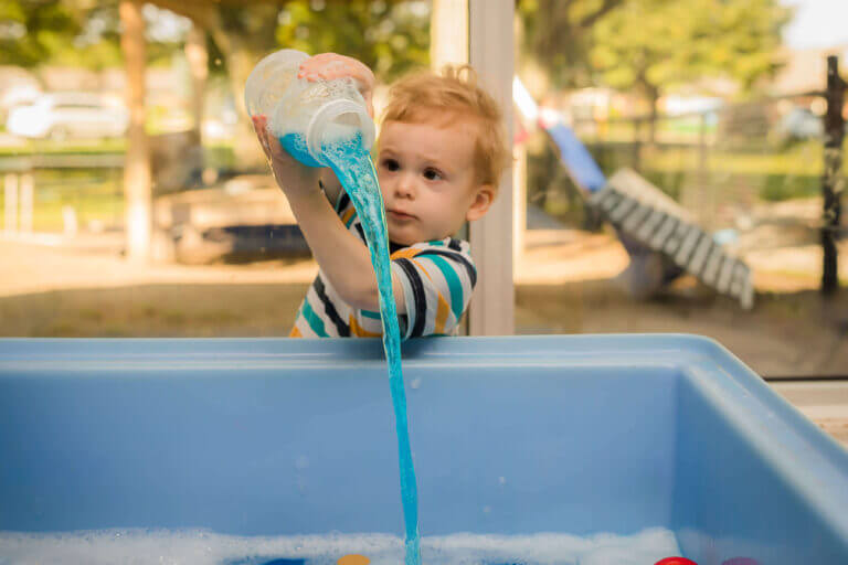 alt='preschool child playing in a water table'
