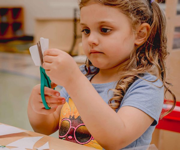 alt='school age child cutting alphabet letters'